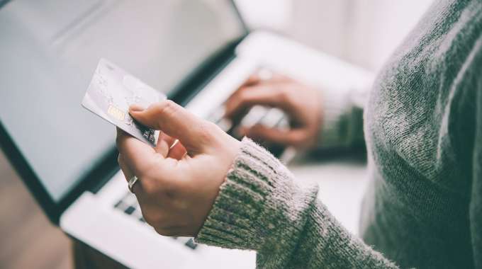 woman types numbers from her first credit card on her laptop
