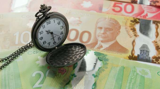 Pocket watch on top of Canadian cash